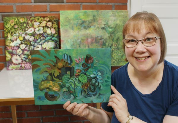 Artist Paivi Eerola, Finland, holding "Back to Nature" and displaying her paintings in progress.