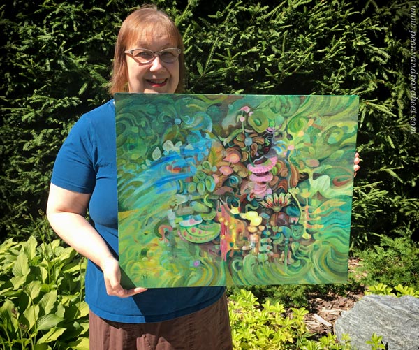 Artist Paivi Eerola holding a painting called Paradise, in her garden.