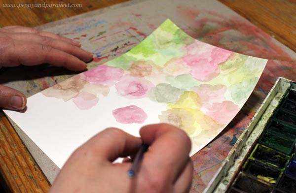 Painting a paper for collage art with watercolors.