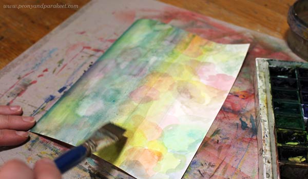 Painting a paper for collage art with watercolors.